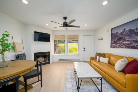 Experience the cozy living room, outfitted with plush seating, a fireplace, an expansive smart TV, and windows that frame the views of the great outdoors.