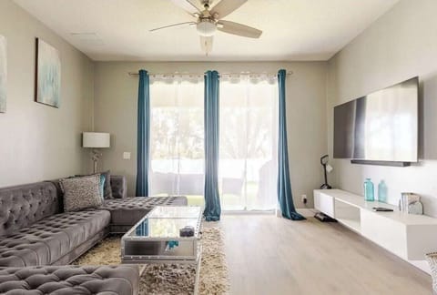 Bright, open living space with plush seating and a large smart TV—perfect for relaxing, movie nights, or unwinding after a day exploring Orlando.
