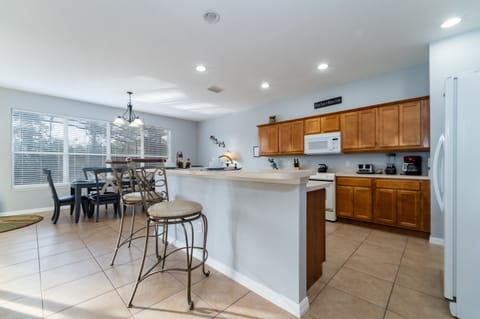Open kitchen and dining area with breakfast bar seating, full appliances, and natural light.