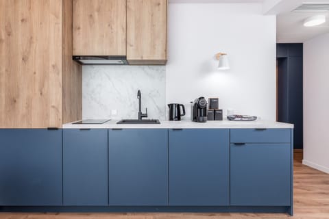 A small kitchenette with wooden finishes and essential appliances, like a coffee maker and kettle.