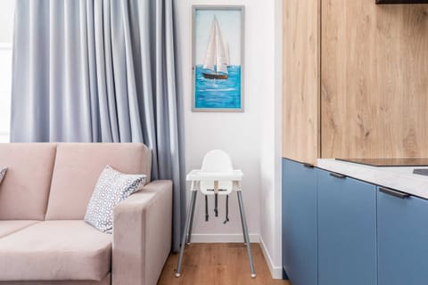 A modern living room with a sofa, armchair, and soft pastel accents, bathed in natural light.