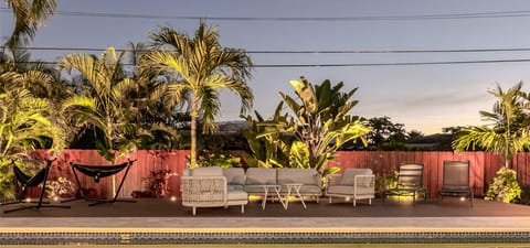 Tropical Fenced in Private Backyard with Heated Pool, uplighting, outdoor dining table, lounge chairs and plenty of seating/hammocks.