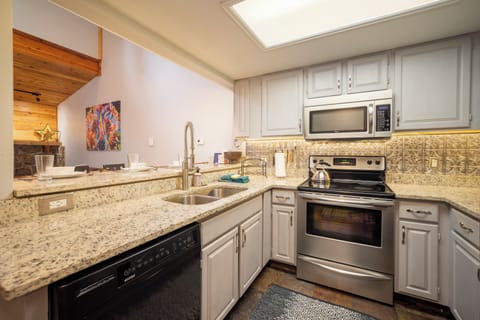Your fully equipped kitchen features granite counters, stainless appliances, and charming tin ceiling tiles, perfect for preparing home-cooked meals.