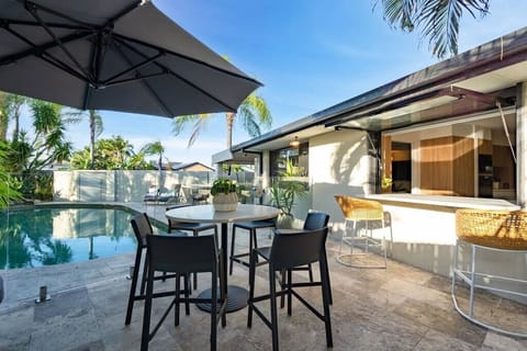 Private pool area with dining, loungers, glass fencing and covered bar.