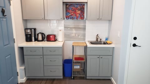 The kitchen area with coffee maker, hot water kettle, toaster, sink, plates,...