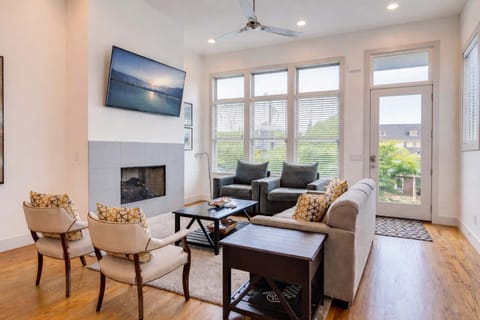 Modern living space with sunlit windows, cozy seating, and entertainment-ready mounted TV.