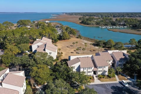 Aerial view of waterfront condominiums surrounded by trees and marshland.