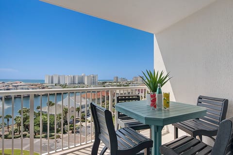 Elevated beachfront balcony with city views and outdoor dining table for four guests.