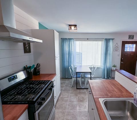 Kitchen and Dining with large window for plenty of natural light. Gas stove for cooking with pots/pans, spices, and cooking oil.
