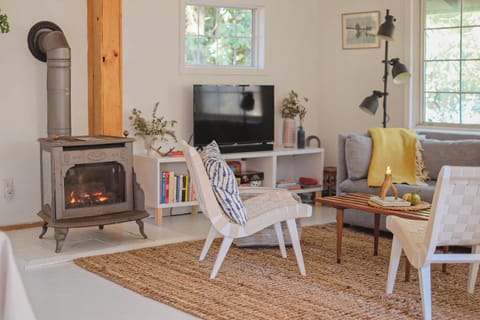 The living/dining room and kitchen have been opened up to one big space and the living room part features a gas fireplace, comfy sofa and chairs,  smart TV and speaker. 