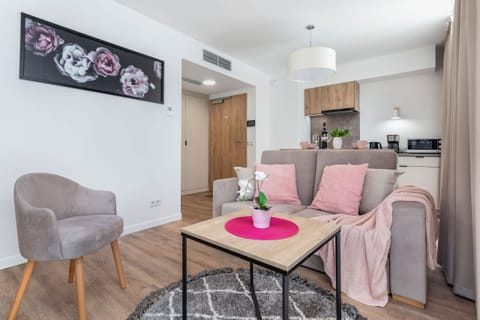 A modern living room with a gray sofa, pink accents, and a dining area, creating a cozy atmosphere.
