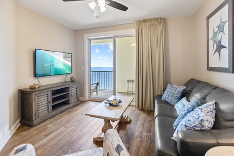 Relax in your coastal living room with ocean views through sliding doors, comfortable seating, and entertainment center.