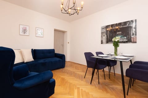 A cozy living room with navy blue armchairs, a table, and elegant lighting.
