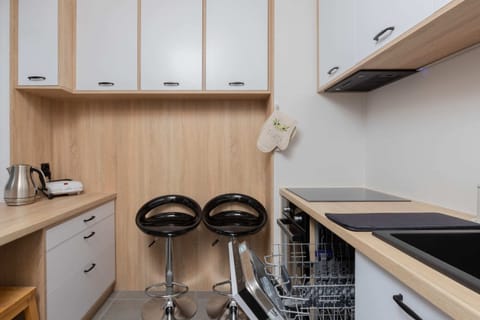 A compact kitchen featuring modern appliances, white cabinets, and a neutral wooden countertop.