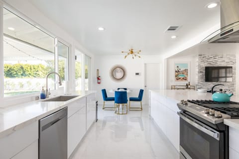 Share your culinary skills in the open-concept chef’s kitchen, featuring sleek white countertops, modern stainless steel appliances, & plenty of natural light. With stylish blue chairs, perfect for meals and conversation.