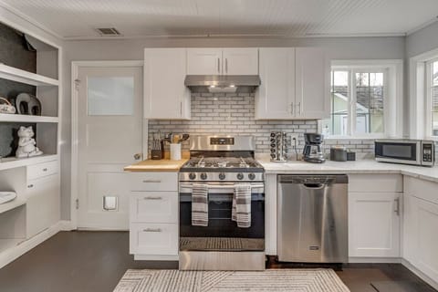 Stocked kitchen with spice rack, knives, cooking utensils, coffee corner, fridge, oven, stove, and microwave