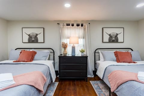 Charming and spacious bedroom featuring two queen beds, smart TV, dresser and Armoire
