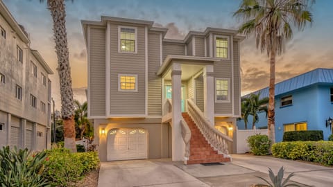 The home's front exterior glows under twilight, welcoming you with warm, inviting island lighting.