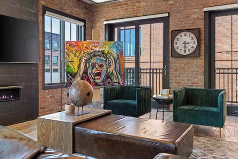 Chic and stylish living area featuring exposed brick walls, comfortable lounge seating with a fireplace, a Smart TV, a vintage record player, and direct access to your private balcony