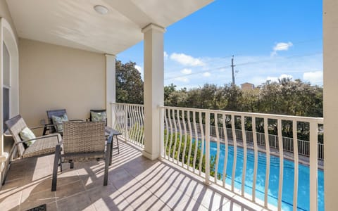 Relax on your private balcony with wicker seating while enjoying stunning pool views and lush surroundings.