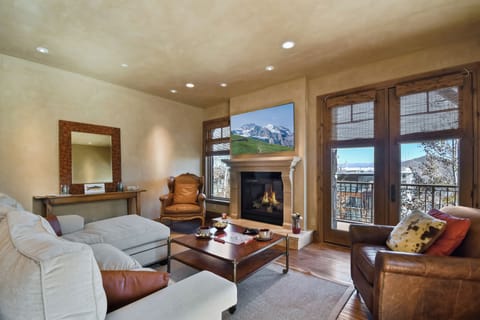 Unwind in the heart of the home, where soaring windows frame mountain views, a warm fireplace invites relaxation, and comfortable seating creates the perfect gathering space after a day on the slopes.
