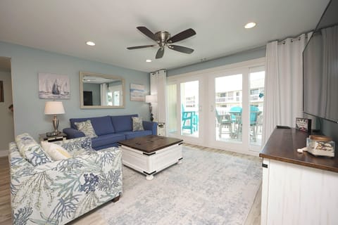 Unwind in your coastal living room with soothing blue decor, comfortable seating, and balcony access to turquoise outdoor furniture.