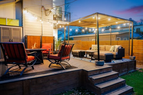 Cozy outdoor patio with string lights, firepit, and cushioned seating, perfect for relaxing evenings