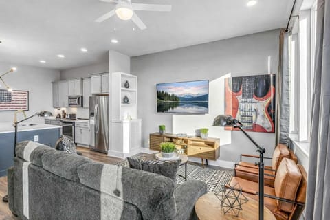 Sunlit lounge with a wall-mounted TV and unique painted guitar artwork.