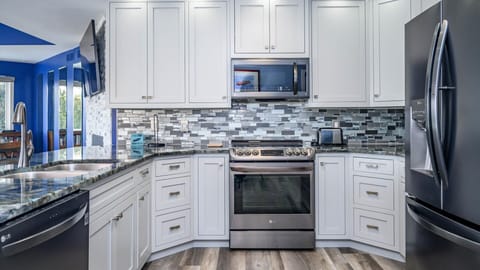 Glass top electric oven range. Cabinets are full of all the accouterments needed for your gourmet cooking experience.