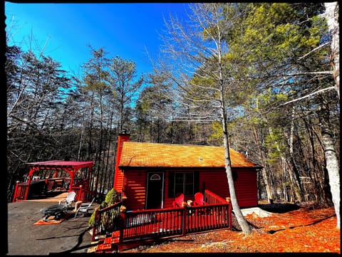 Front of cabin features patio with Adirondack chair, Fire Pit & Pergola w/ BBQ