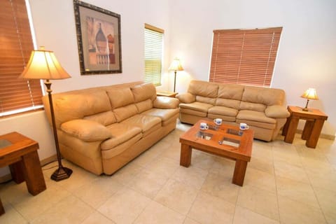 The living room showcases high ceilings and a tile fireplace. Perfect for gathering after using the community pool or jacuzzi .