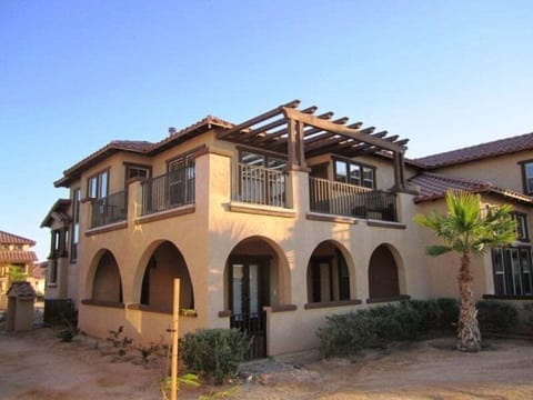 The rear of this vacation rental home offers a spacious patio with seating, direct access to a greenbelt, and views of the surrounding