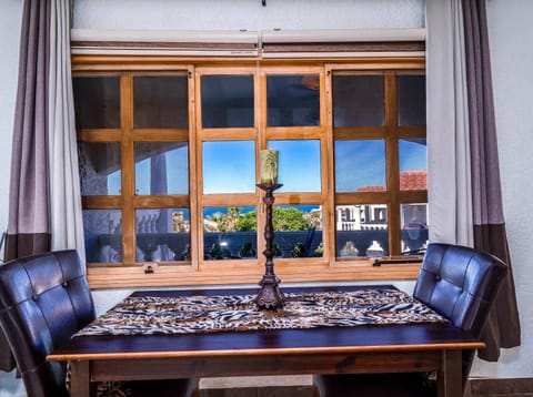 The eat-in kitchen features a classic dining table for four, conveniently located by large windows overlooking the sparkling community pool