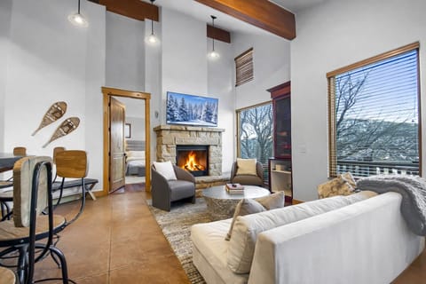 Unwind by your crackling stone fireplace in this modern mountain retreat, where soaring ceilings and cozy furnishings create the perfect alpine escape. Unit A