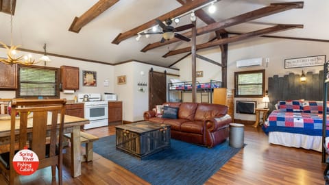 One large room with a full kitchen, large dining table, couch, and beds.