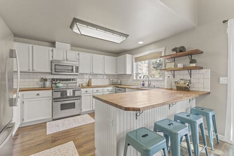 Fully stocked kitchen with butcher block island, bar seating, and farmhouse dining table right next to it