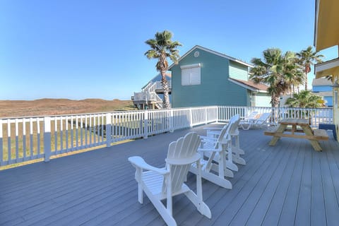 Spacious deck with Adirondack chairs perfect for morning coffee and sunset watching, surrounded by swaying palms and coastal views.