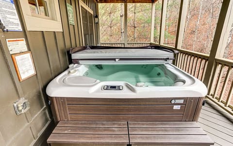 Private hot tub on covered deck with serene forest views.