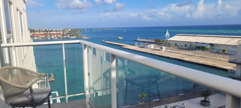 Step onto your private balcony and take in sweeping views of turquoise waters, docked sailboats, and a vibrant coastal harbor—your perfect retreat awaits.