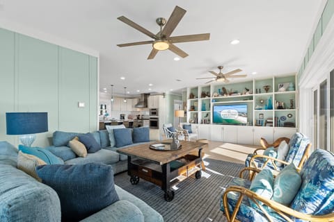 Relax in your coastal living room with plush blue sofas, custom entertainment center, and soothing sea-inspired décor.
