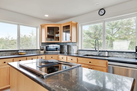 Cook your favorite meals in this fully equipped kitchen featuring granite countertops, modern appliances, and lovely tree views through expansive windows.