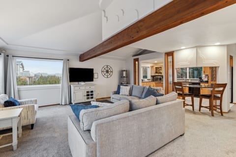 Cozy up on plush sectional seating beneath rustic exposed beams, with your open kitchen just steps away for effortless entertaining.