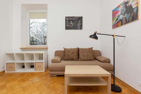 A cozy living room with a sofa, a wooden coffee table, and large windows letting in natural light.

