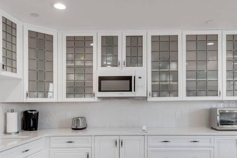 Fully stocked kitchenette with glasses, microwave, Refrigerator, Keurig coffee maker, glasses, plates, and cutlery