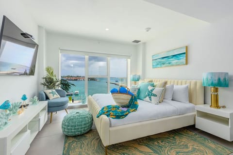 Step into your serene coastal retreat, where floor-to-ceiling windows frame stunning turquoise waters and soft ocean breezes. Your stylish bedroom invites relaxation with plush bedding, calming hues, and beach-inspired décor.