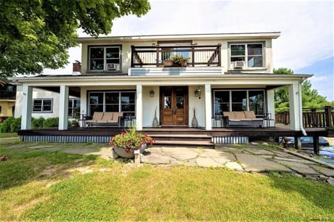 Front of home showcasing upstairs balcony and main floor wrap around porch