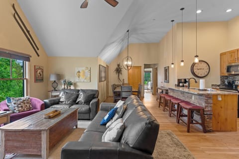 Relax in your spacious open-concept living area featuring vaulted ceilings, cozy leather seating, and a fully equipped kitchen with granite countertops.