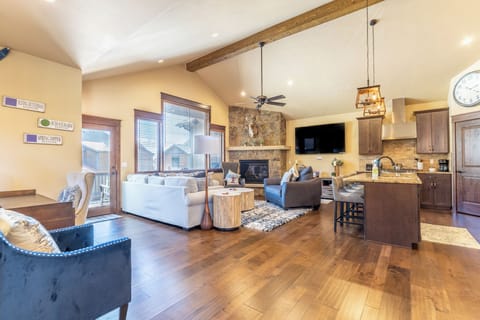 Relax in your open-concept living space featuring rustic beams, stone fireplace, and modern kitchen—perfect for memorable gatherings.