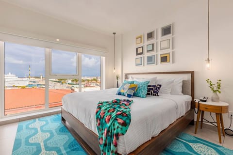 Bright modern bedroom with cheerful pops of color, cozy linens, and a soothing view to help you unwind after exploring the local landmarks.