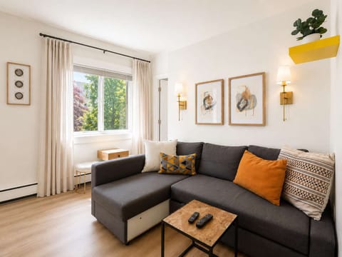 Unwind in a cozy living room featuring a plush charcoal sectional sofa, vibrant pops of color, and great natural light.